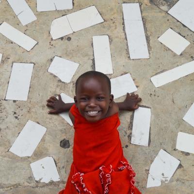During a Projects Abroad Care placement a child poses outside a care centre in Tanzania. In an project volunteering with children in Tanzania a child smiles outside a care centre.